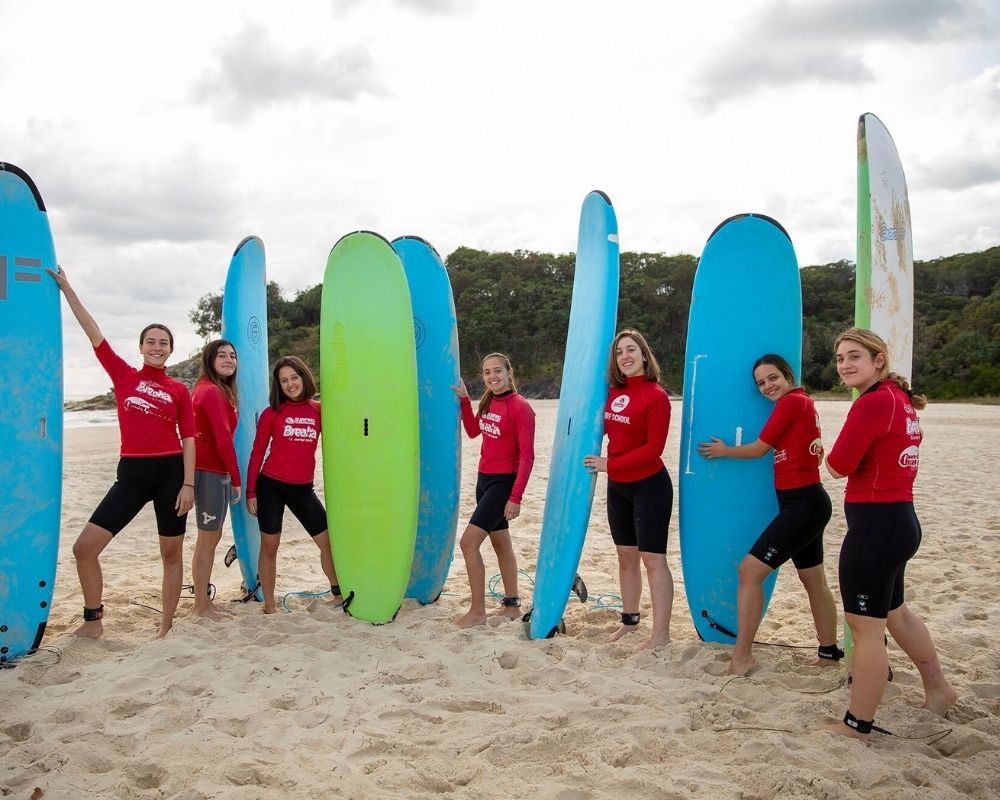 grupo de chicas australianas en la playa preparándose para surfear