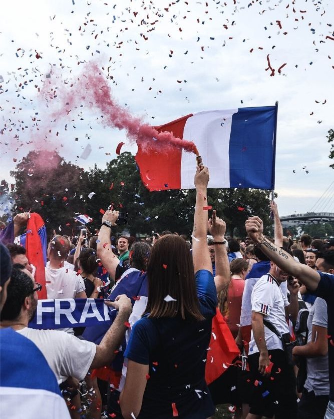 Persone festeggiano la festa nazionale francese con cori, coriandoli e fumi colorati