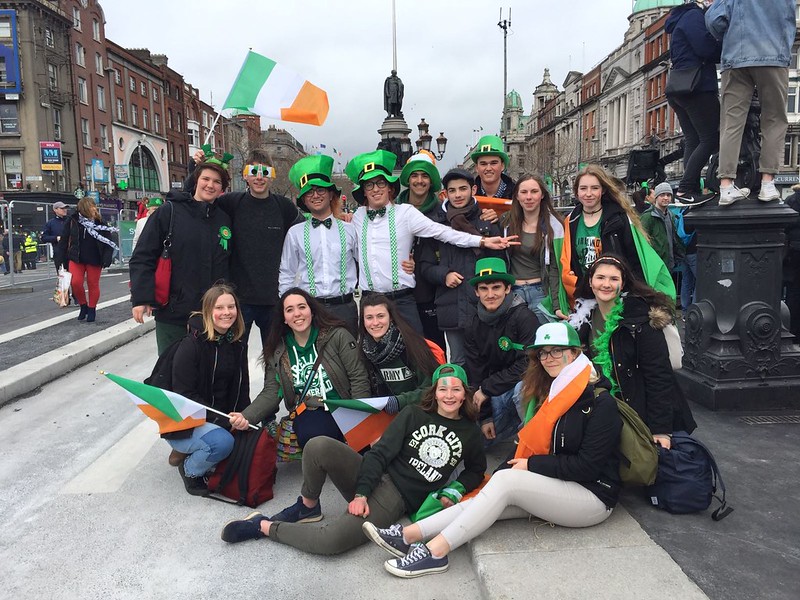 Un gruppo di ragazzi e ragazze con cappelli verdi e bandiere irlandesi posano nelle strade di Dublino durante la festa di San Patrizio