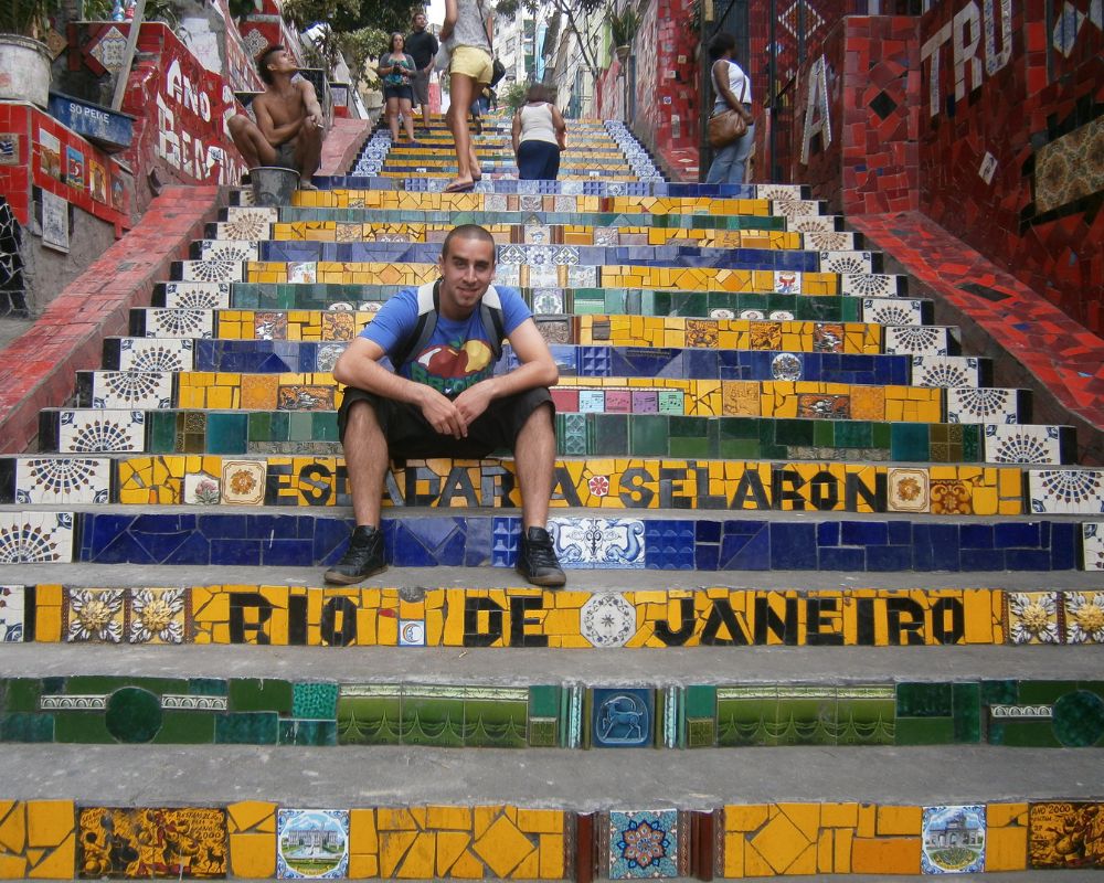 Ragazzo seduto su una scalinata decorata con scritte e colori della bandiera brasiliana