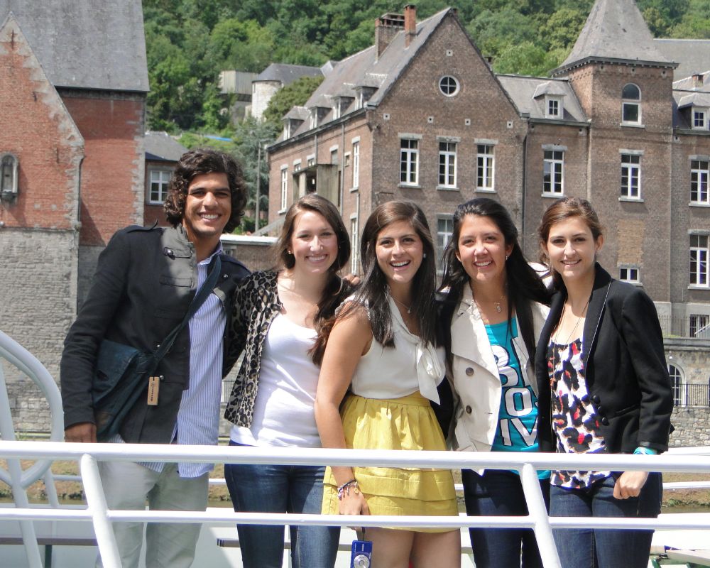 Exchange students e ragazzi belgi in posa in una cittadina storica del Belgio, con un palazzo marrone con finestre bianche e tetto a punta sullo sfondo