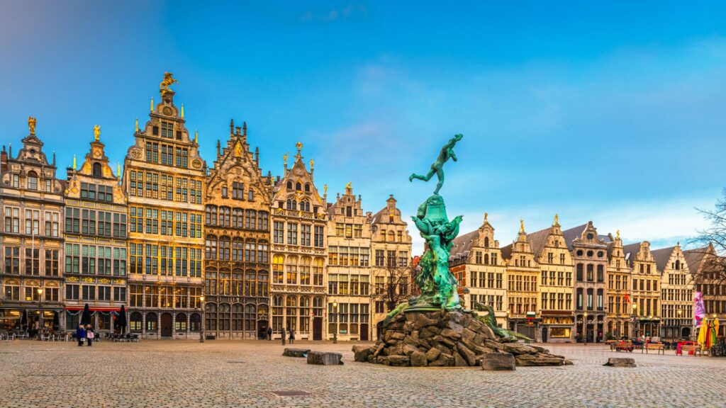 Piazza del Mercato Grande di Anversa, Belgio, con architetture ora gotiche e ora rinascimentali. Al centro la Fonatana di Brabone. Cielo turchese sullo sfondo