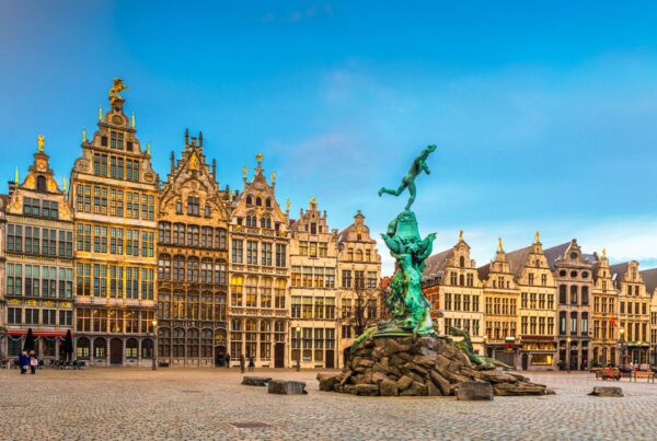 Piazza del Mercato Grande di Anversa, Belgio, con architetture ora gotiche e ora rinascimentali. Al centro la Fonatana di Brabone. Cielo turchese sullo sfondo
