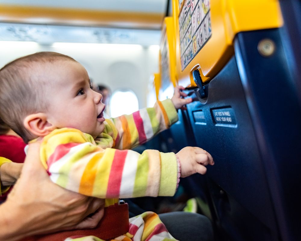 Cosa fare in aereo per passare il tempo: un bambino di pochi mesi gioca con il sedile anteriore su un aereo Ryanair