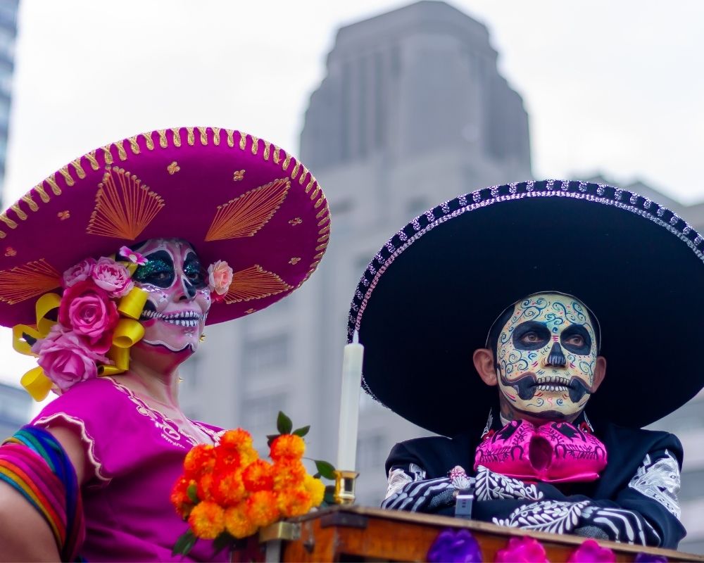 Due maschere vestite a festa in occasione del Giorno dei Morti in Messico: indossano i tipici cappelli messicani e hanno una maschera a forma di teschio