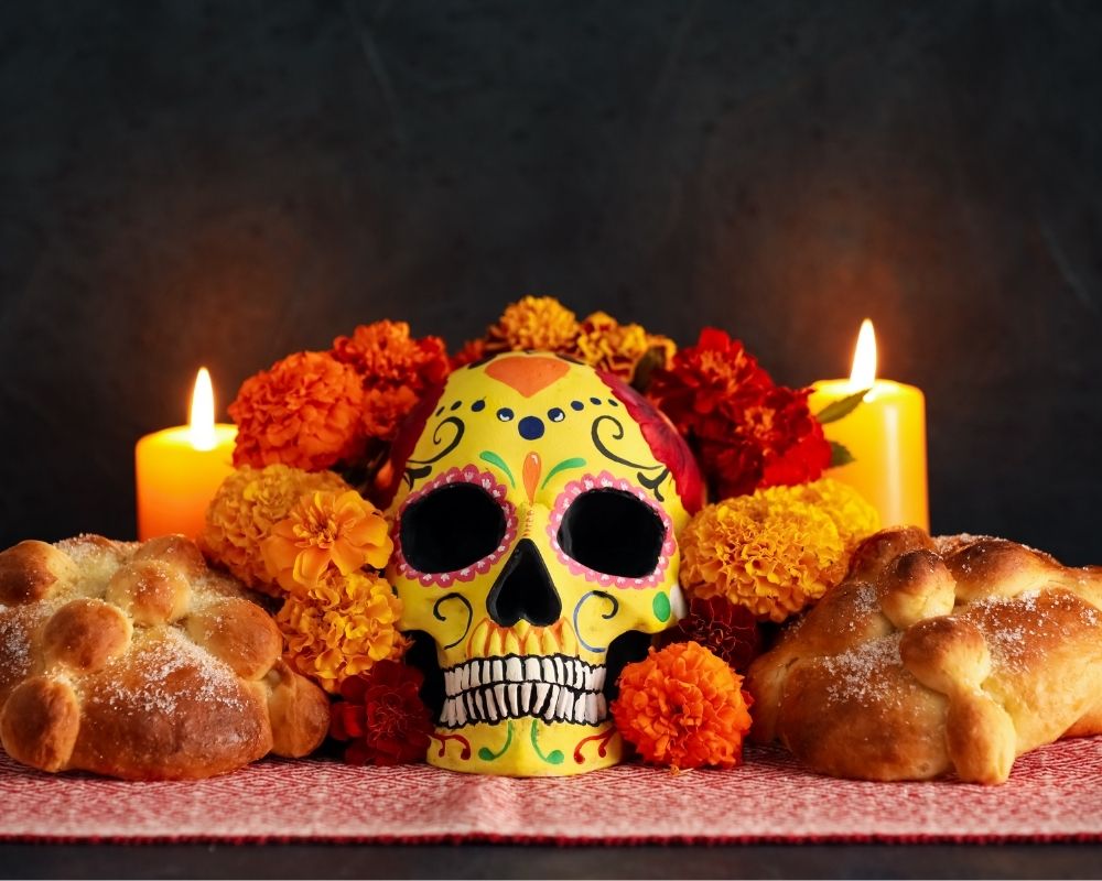 Teschio dipinto di giallo con decorazioni colorate, candele e pani realizzato in occasione del Giorno dei Morti in Messico