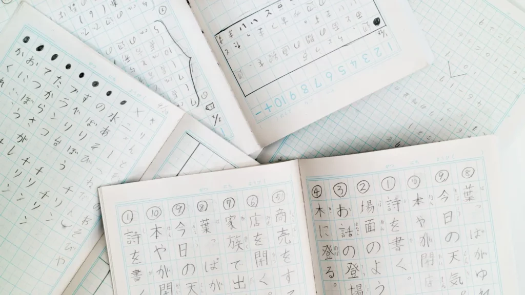 Quaderni aperti con riquadri riempiti con caratteri dei sistemi di scrittura giapponesi. Si tratta di esercizi di scrittura