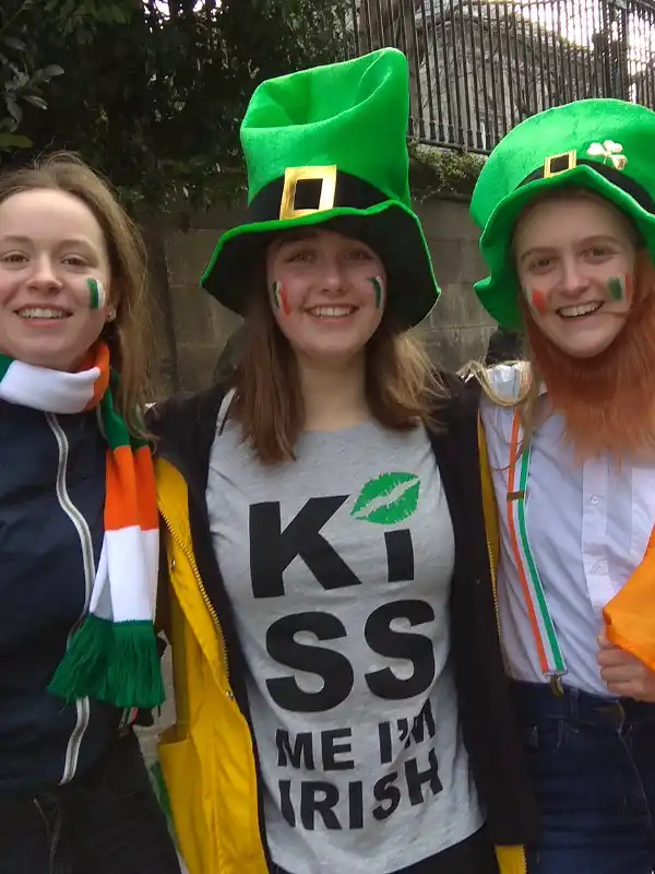 Tre ragazze in posa per San Patrizio in Irlanda con costumi del santo, bandiere disegnate sulle guance.