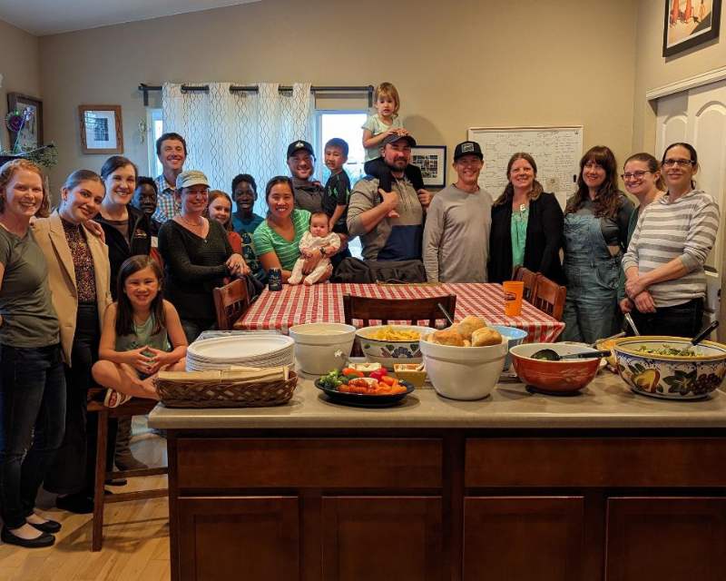 Numerosa famiglia riunita per scattare una foto ricordo in occasione del Thanksgiving, di fronte un tavolo imbandito con pietanze