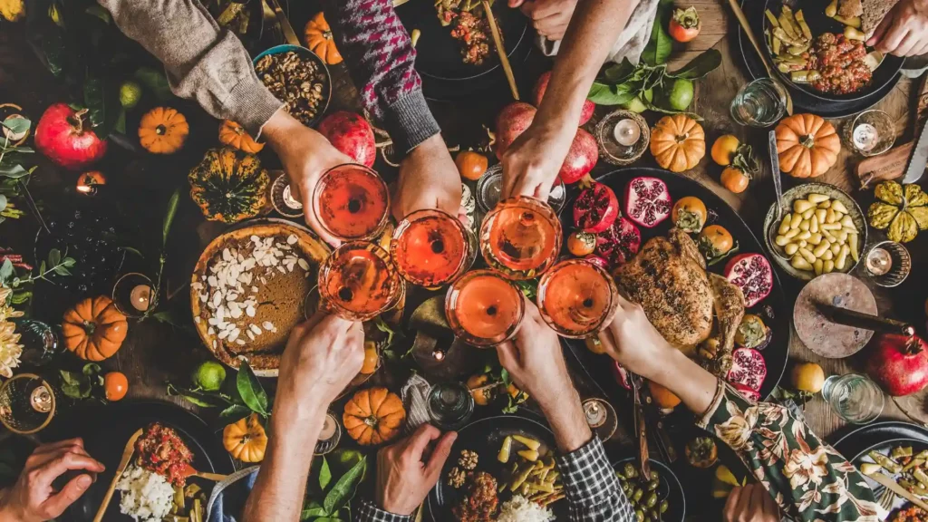 Tavola imbandita per il Thanksgiving in America con bicchieri in centro intenti in un brindisi, clima di festa