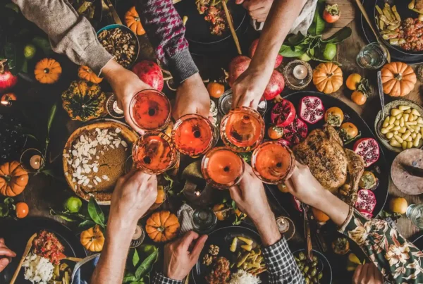 Tavola imbandita per il Thanksgiving in America con bicchieri in centro intenti in un brindisi, clima di festa