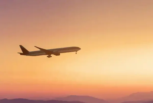 Aereo che vola sopra una catena montuosa al tramonto, con il carrello d’atterraggio già abbassato