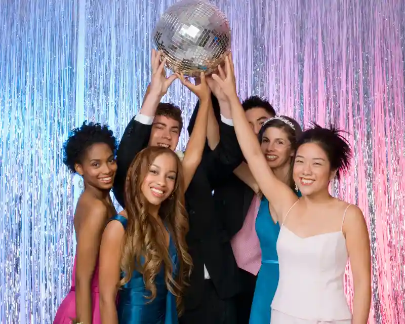 Ragazze e ragazzi in vestiti da ballo di fine anno sorreggono una palla da discoteca. Il Prom è l’evento simbolo dei balli di fine anno.