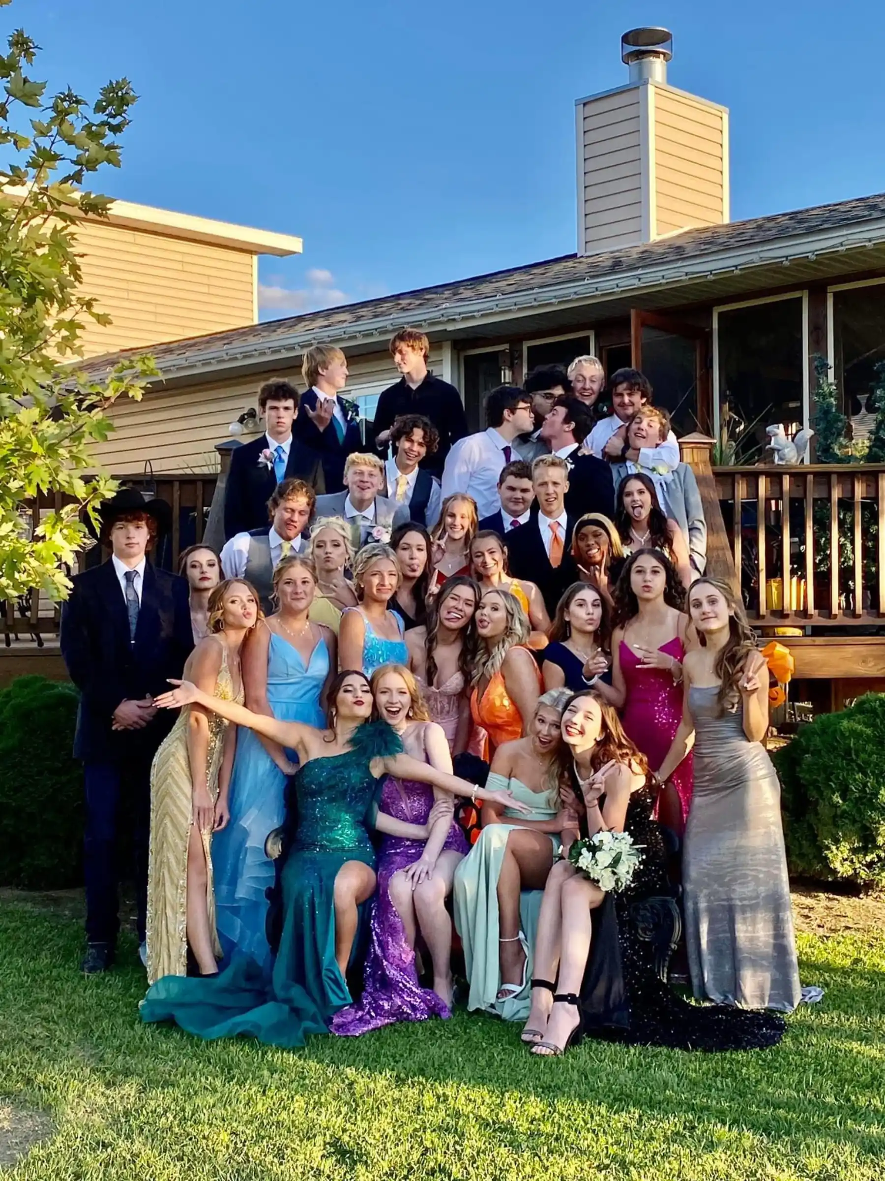 Ragazzi e ragazze posano in abiti eleganti davanti a una casa, pronti a vivere il Prom, il ballo di fine anno americano.