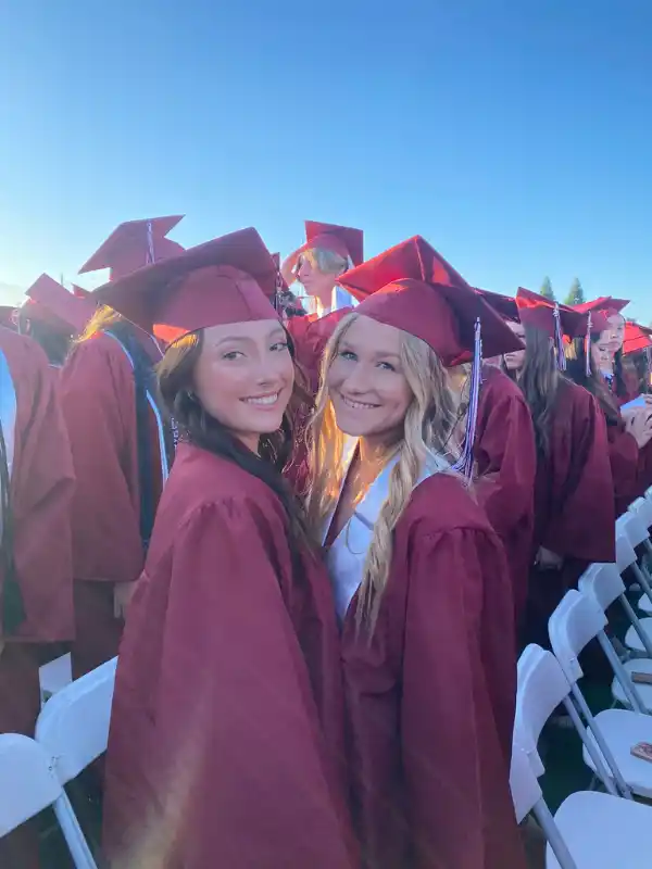 Due studentesse sorridenti in toga rossa partecipano al graduation day negli Stati Uniti.