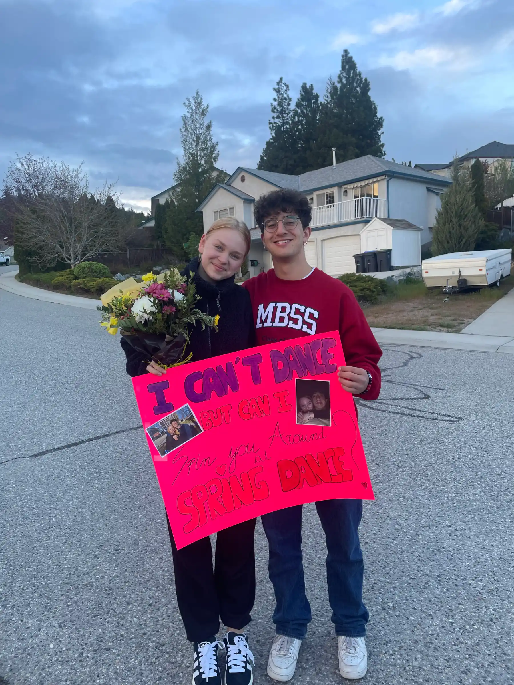 Una ragazza riceve un bouquet e un cartellone rosa durante un promposal, tradizione divertente che anticipa il Prom, ballo di fine anno.