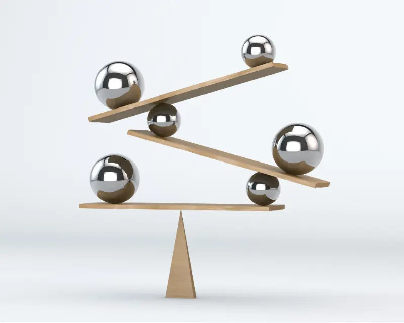 Sfere in equilibrio su assi di legno come metafora del rapporto genitori figli, tra fiducia e sostegno.