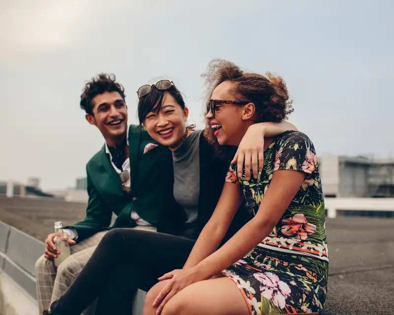 Tre ragazzi di culture diverse sorridono insieme: fare amicizia all’estero significa scoprire la bellezza della diversità