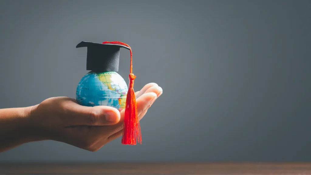 Una mano sorregge un globo con tocco di laurea, simbolo del rapporto genitori figli fondato su crescita e indipendenza.
