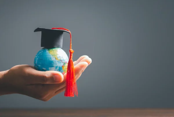 Una mano sorregge un globo con tocco di laurea, simbolo del rapporto genitori figli fondato su crescita e indipendenza.