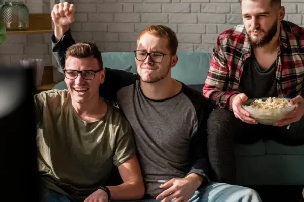 imparare-il-tedesco-con-le-serie-tv Tre amici delle scuole superiori stanno sul divano mentre si divertono a mangiare pop corn e a imparare il tedesco con una serie TV