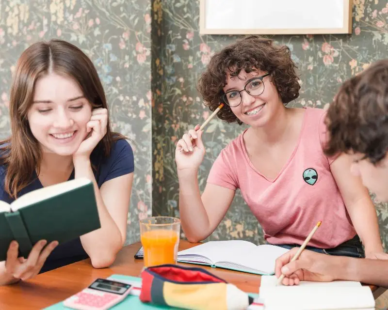 Studenti che studiano tedesco imparando dai libri, seduti a un tavolo in aula studio