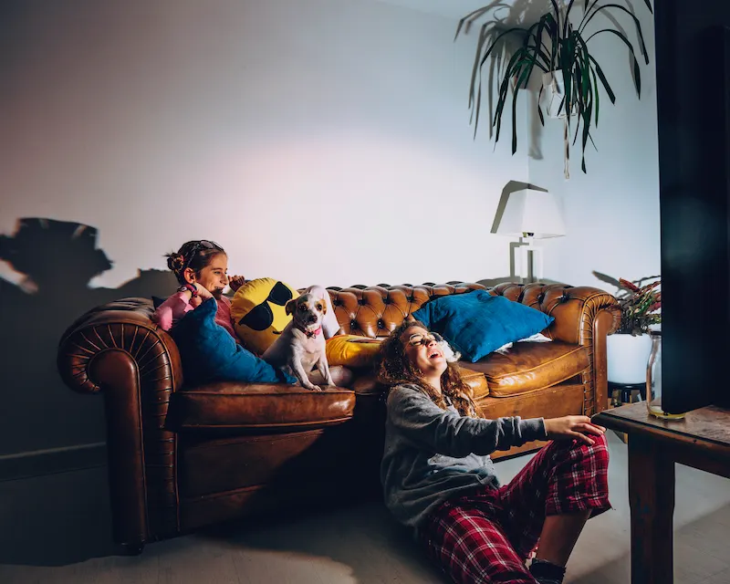 Due sorelle guardano serie tv in francese con il cane, imparando la lingua comodamente dal divano di casa