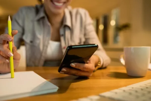 Ragazza adolescente sorridente sta studiando tedesco con l'uso di un'applicazione.