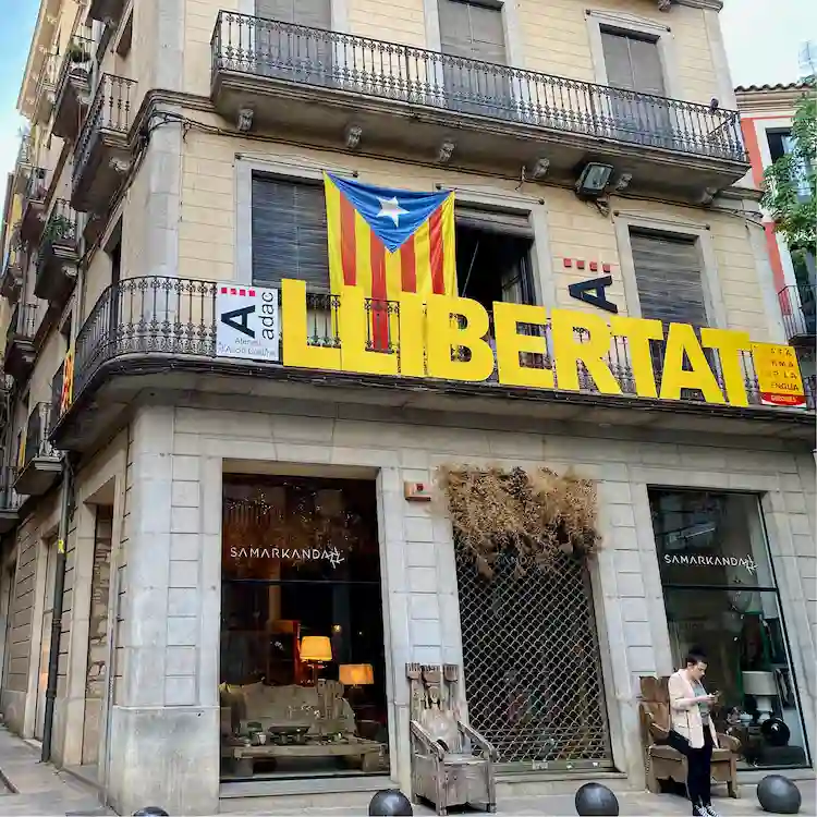 Edificio con bandiera catalana e striscione Llibertat a Girona, esempio della lingua catalana tra le lingue in Spagna