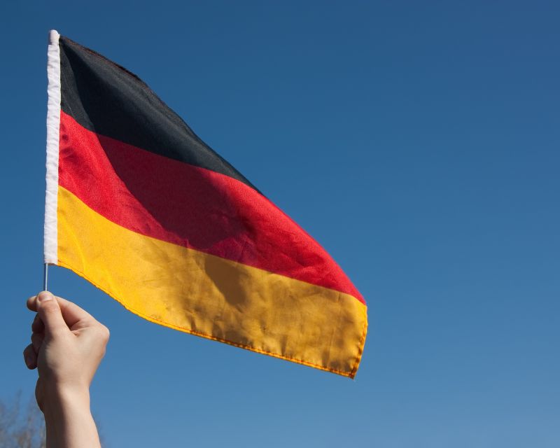 Mano che sventola una bandiera tedesca a strisce nera rossa e dorata, simbolo della Germania