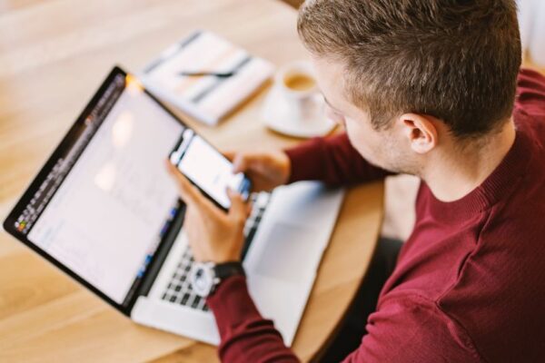 Migliori app per imparare il tedesco Ragazzo con capelli a spazzola e maglietta rossa a maniche lunghe cerca sul telefono un'app per imparare il tedesco.