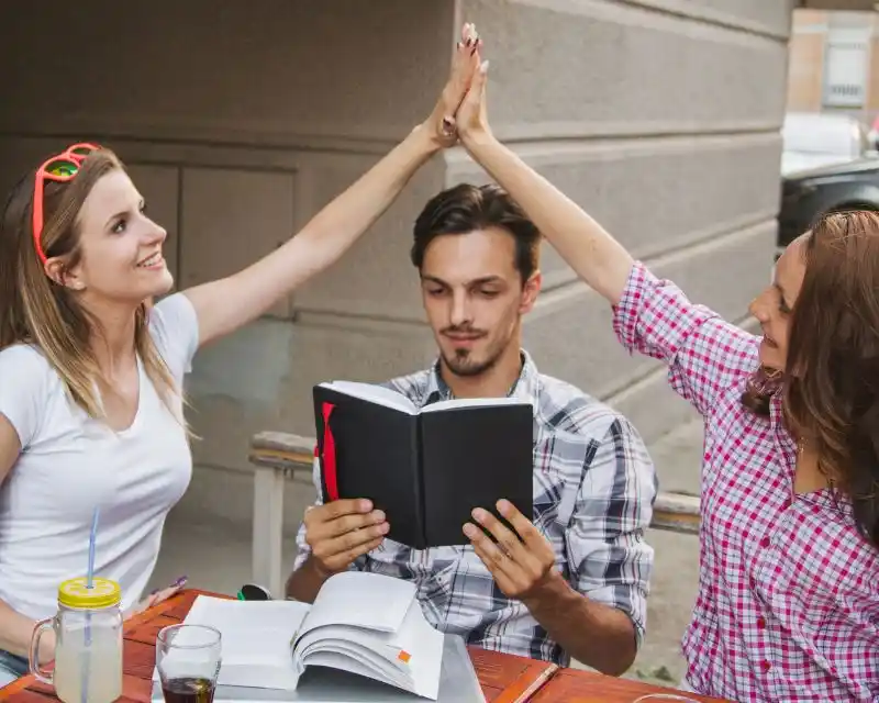 Tre amici che frequentano le scuole superiori stanno leggendo un libro per memorizzare modi di dire in tedesco