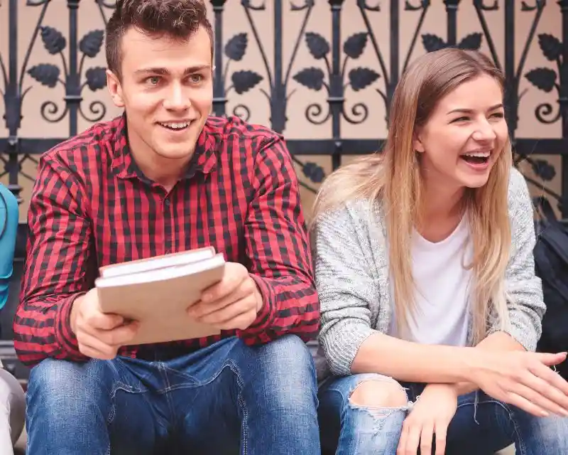 Due amici, un ragazzo con una camicia a quadri e una ragazza con i capelli biondi lunghi, si divertono a capire modi di dire bizzarri in tedesco