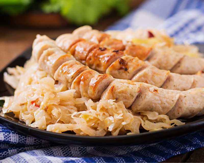 Crauti e salsiccia serviti su un piatto nero: sono uno dei simboli della cucina tedesca