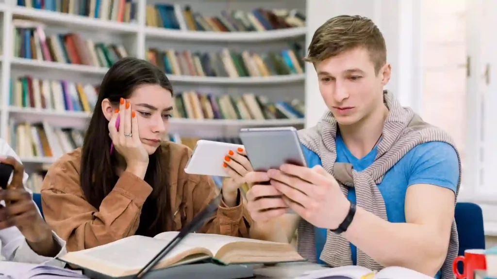 Un ragazzo e una ragazza stanno studiando in biblioteca cercando di imparare il francese con un'app.
