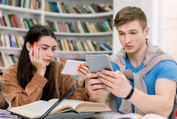 Un ragazzo e una ragazza stanno studiando in biblioteca cercando di imparare il francese con un'app.