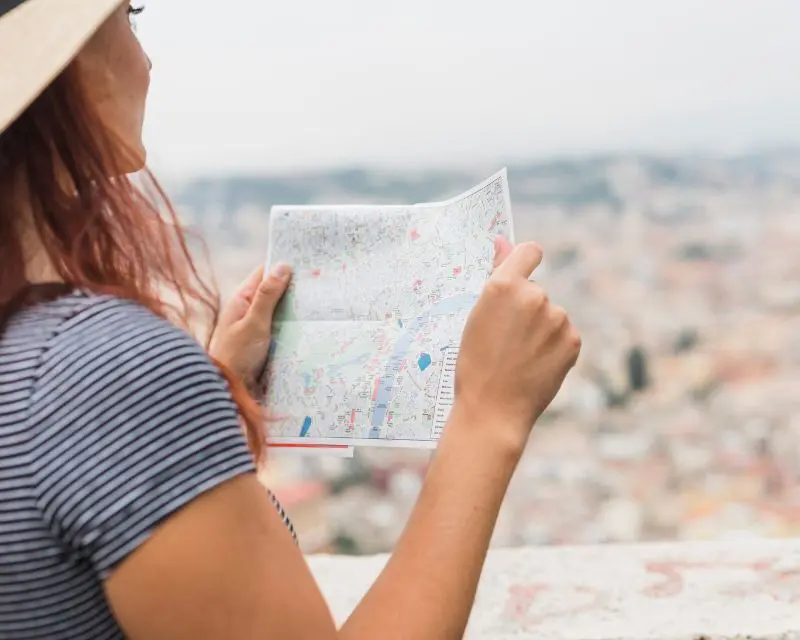 Ragazza alla scoperta della curiosità della Francia preferisce orientarsi per strada guardando una cartina.