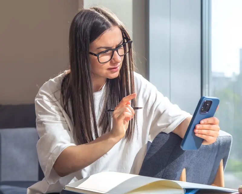 Ragazza con gli occhiali, i capelli lisci e una maglia bianca cerca di capire quale sia la migliore app per imparare il francese.