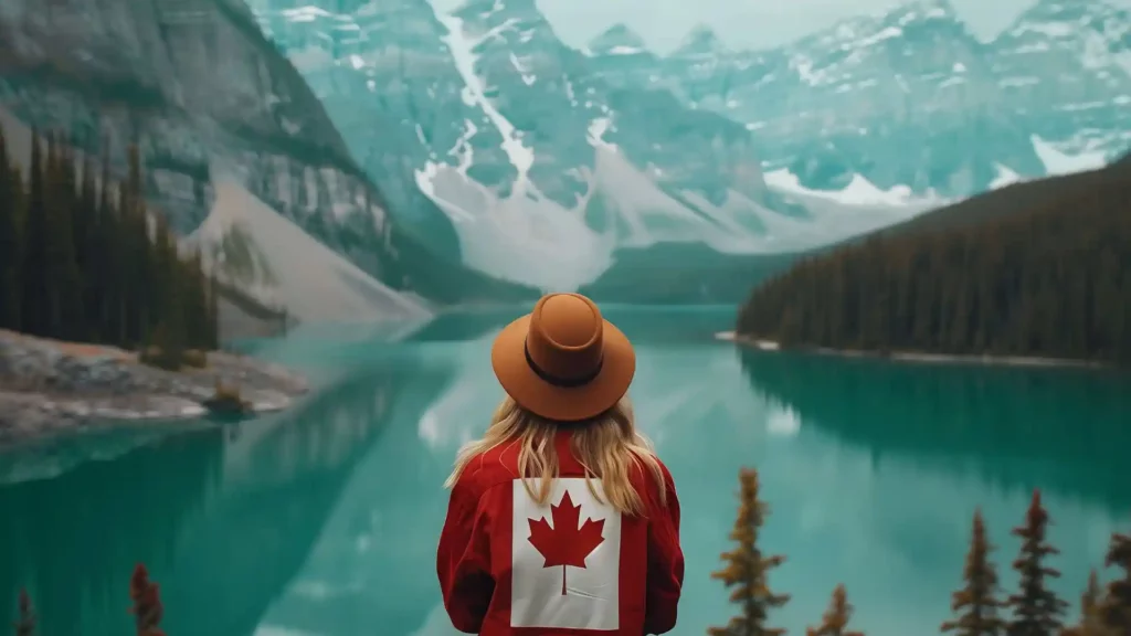Ragazza con capello e felpa del Canada guarda un lago canadese, una delle curiosità su questo Paese è che ci sono 2 milioni di laghi.