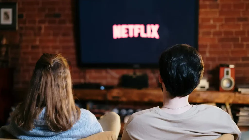 Due persone guardano Netflix sul divano per imparare l'inglese con le serie TV