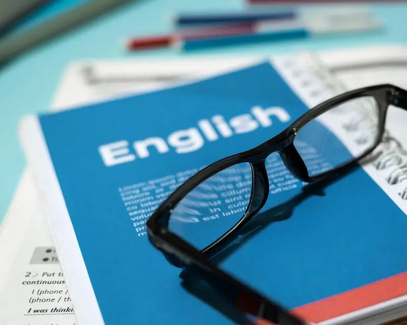 Occhiali da vista neri poggiati su un libro per imparare l'inglese.