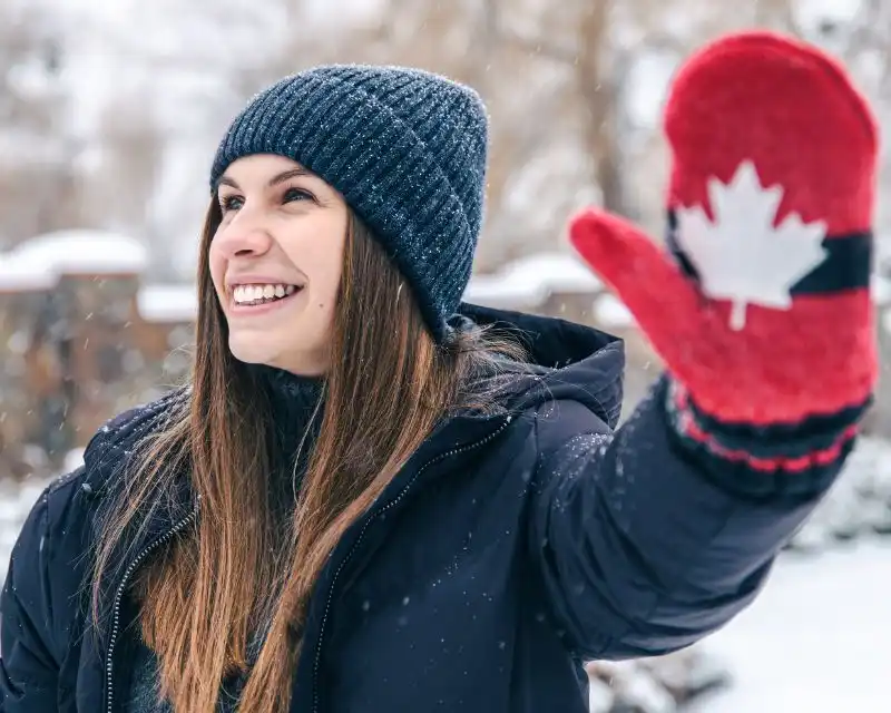 Ragazza con capelli lisci, guanti rossi e capello viaggia alla scoperta degli Stati del Canada.