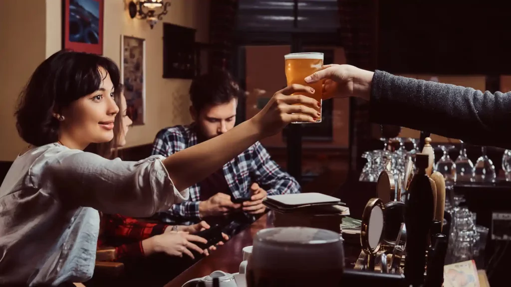 Amici che ordinano una birra al bancone, simbolo della tradizione popolare inglese del pub.