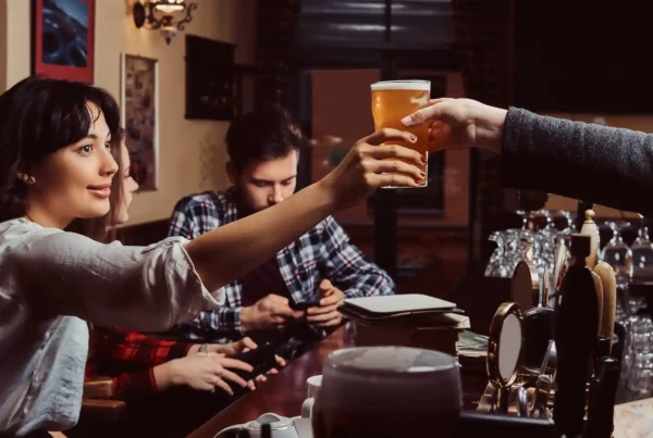 Amici che ordinano una birra al bancone, simbolo della tradizione popolare inglese del pub.