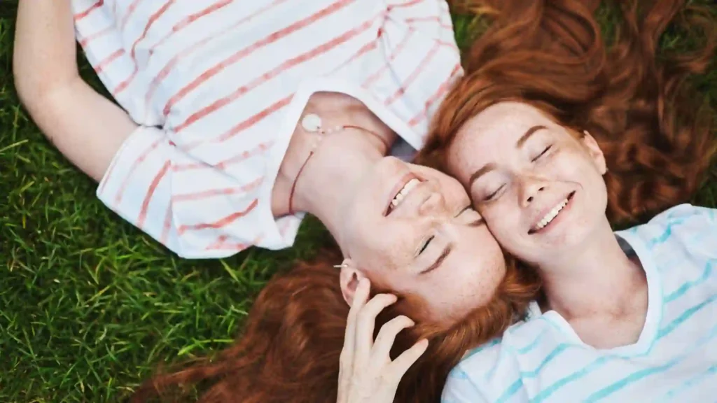Due ragazze gemelle con i capelli rossi distese su un prato. Una delle curiosità sull'Irlanda più incredibile è che il 10% della popolazione ha i capelli rossi.