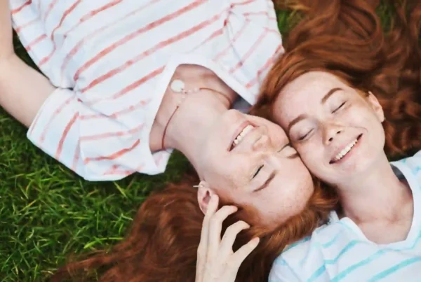 Due ragazze gemelle con i capelli rossi distese su un prato. Una delle curiosità sull'Irlanda più incredibile è che il 10% della popolazione ha i capelli rossi.