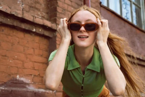 Ragazza con capelli lisci lunghi rossi, occhiali da sole e maglietta verde fa parte della comunità che parla la lingua irlandese oggi.