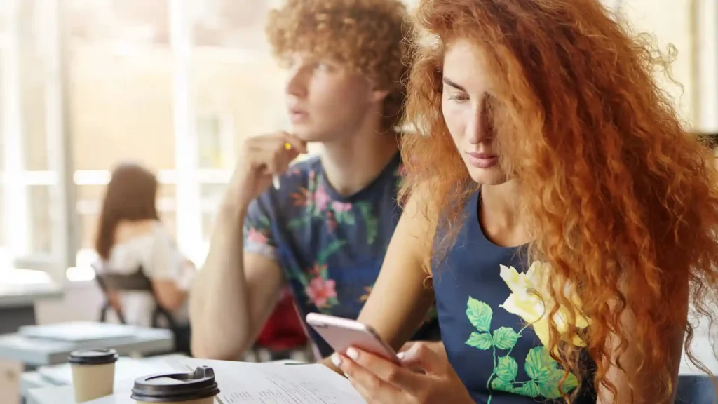 Due studenti in aula che usano lo smartphone per studiare l'inglese con un'app