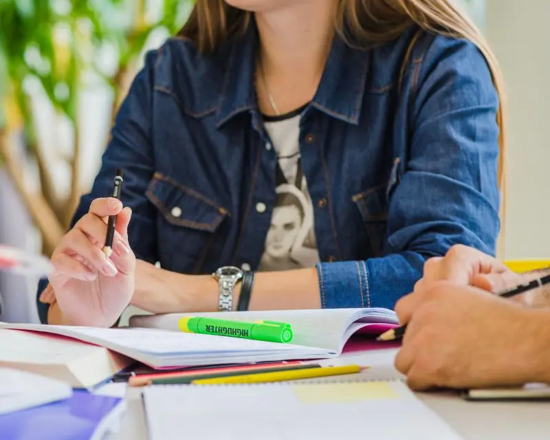 Studentessa con camicia di jeans studia un elenco di parole difficili in inglese.