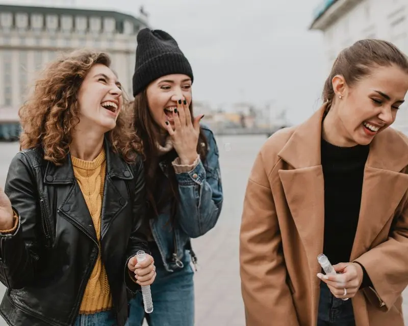 Gruppo di tre amiche con abbigliamento invernale se la ride perché non capisce la pronuncia della lingua irlandese.